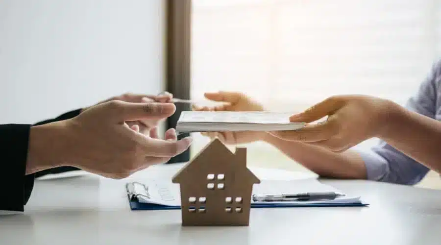 A home passing between two people, representing title moving to a surviving co-owner