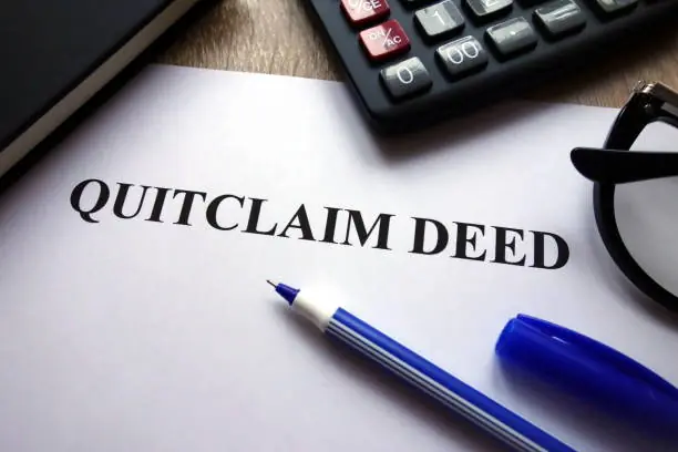 A California quitclaim deed document with a pen, shown beside grant deed comparison